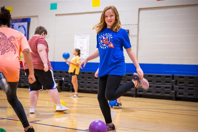 A girl wearing blue kicks the ball